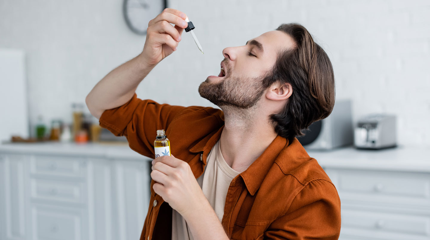 Gros plan de gouttes d'huile CBD tombant d'une pipette dans un flacon ambré